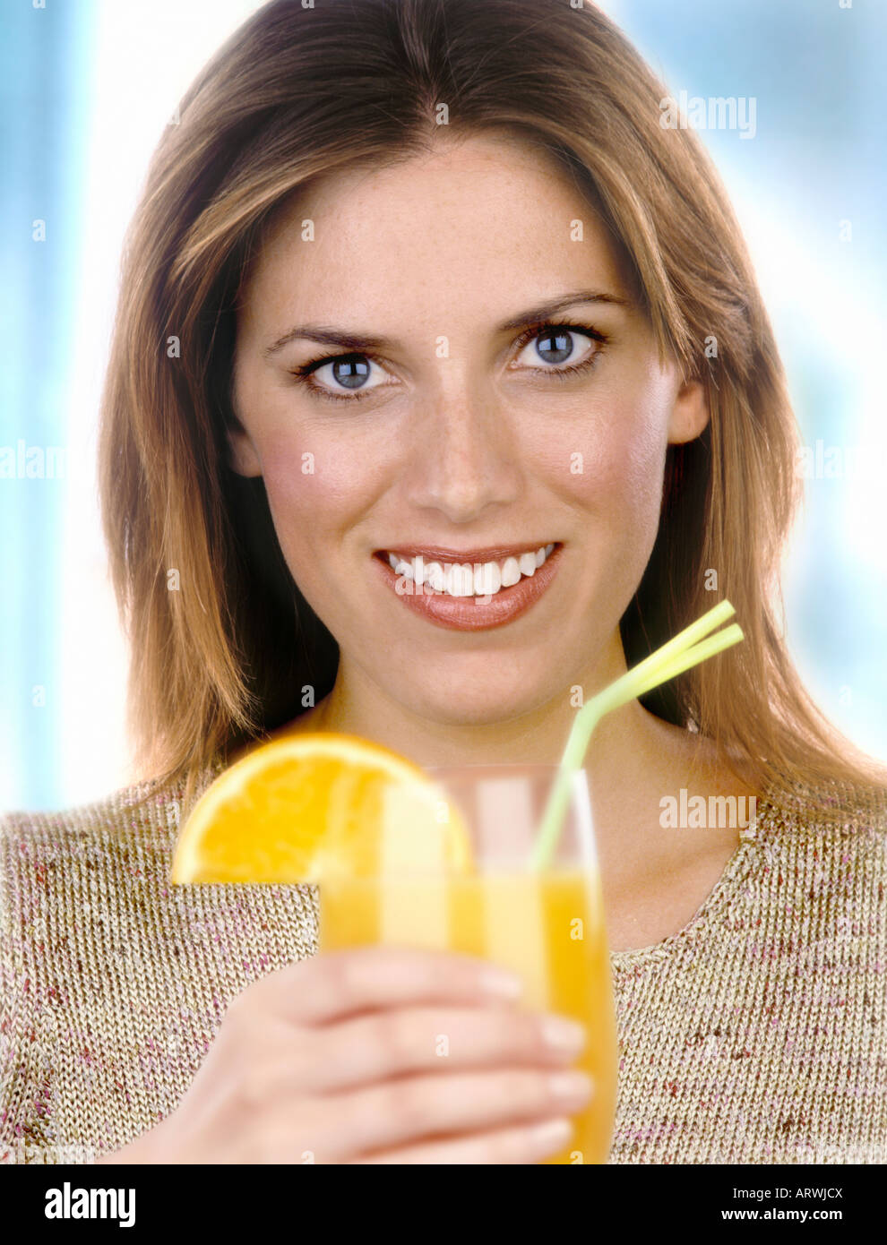 Une femme tenant un verre de jus d'orange avec de la paille Banque D'Images