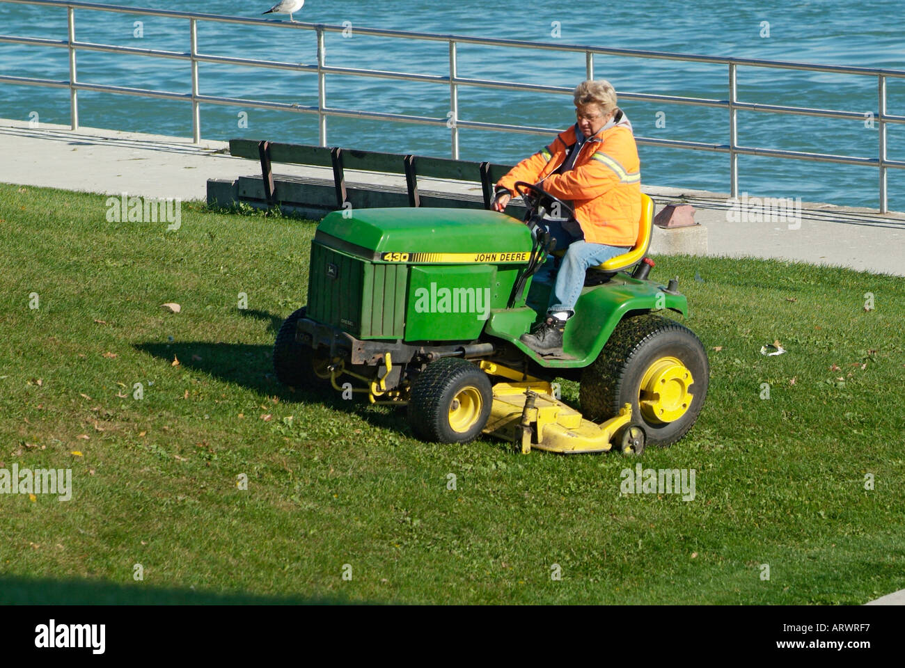 Ville femelle de tonte pelouse travailleur sur un tracteur John Deer coupe herbe Banque D'Images