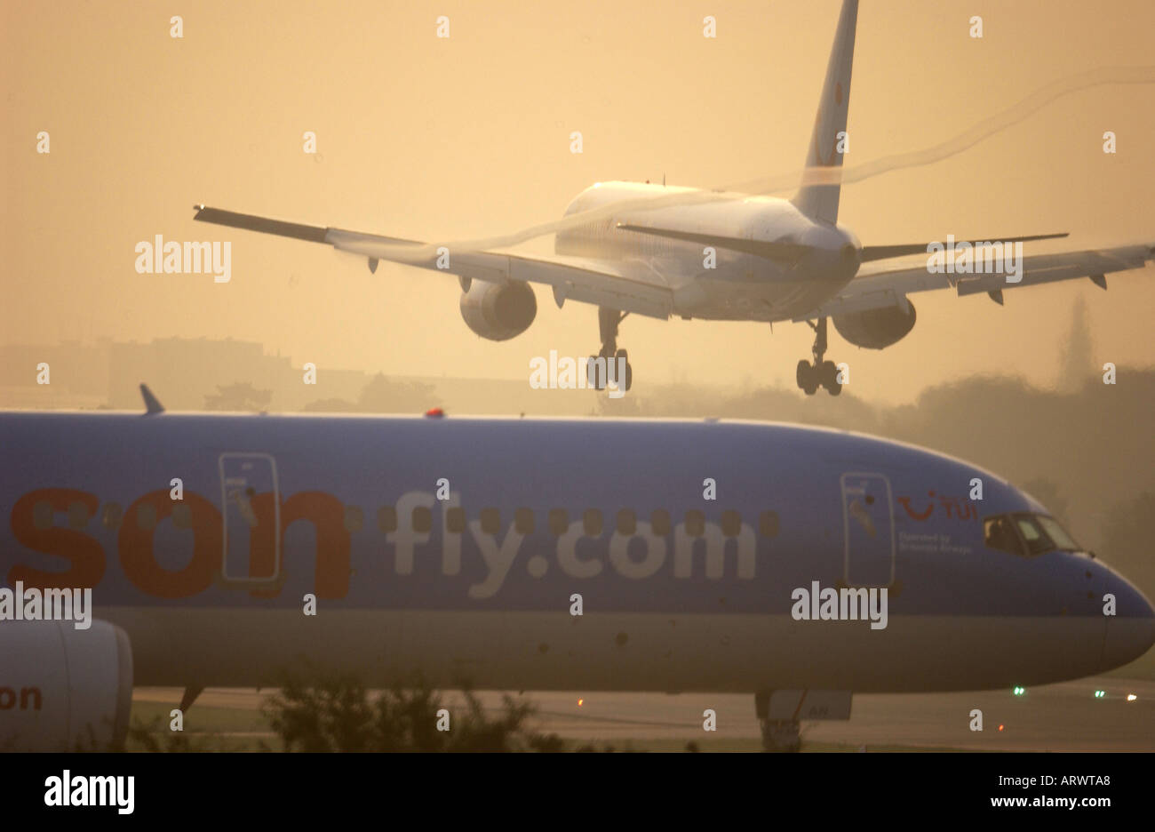 Un Boeing Jet arrive en terre à l'aéroport de Londres Gatwick, à l'aube sur un jet de fly.com Thomson en attente de décollage Banque D'Images