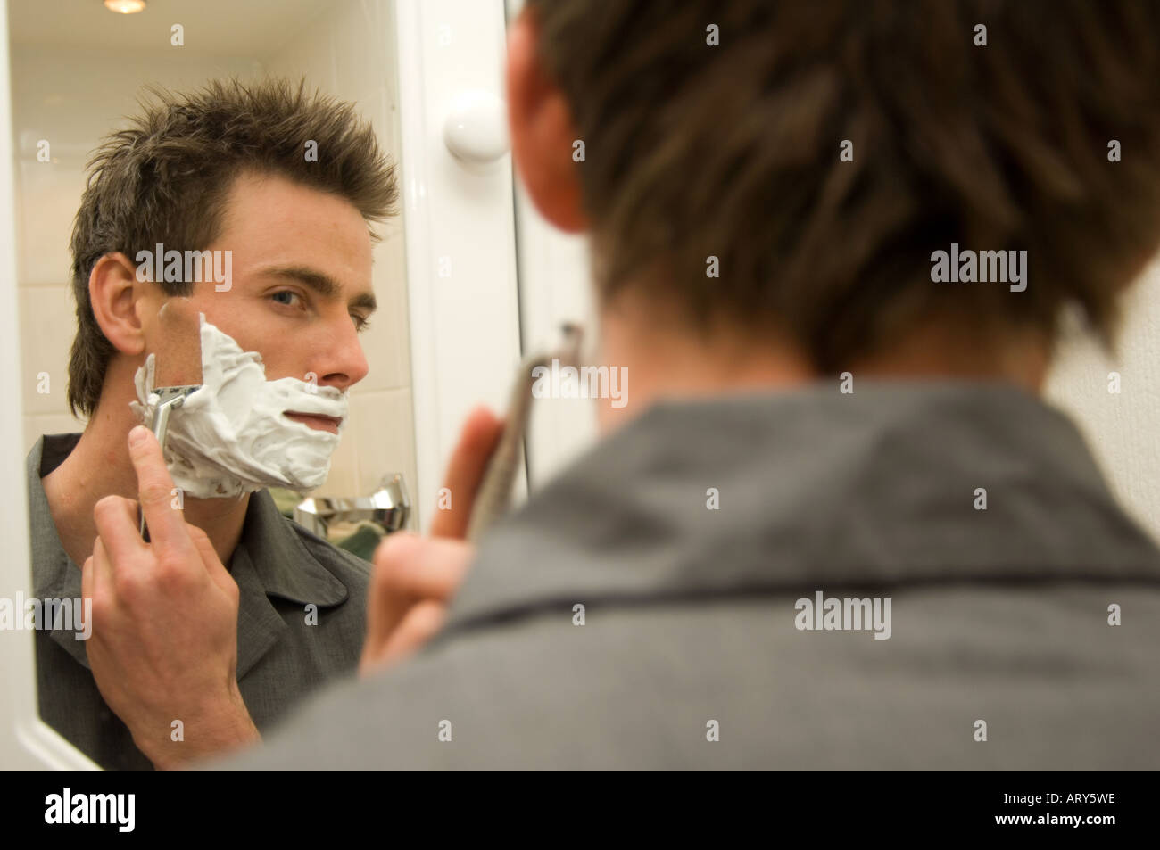 L'homme à la recherche d'une salle de bains miroir grossissant et de rasage Banque D'Images