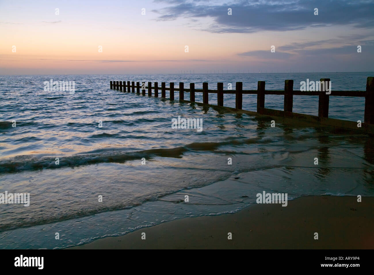 Plage et brise-lames à la brunante avec wind farm sur horizon Muro North Wales UK Banque D'Images