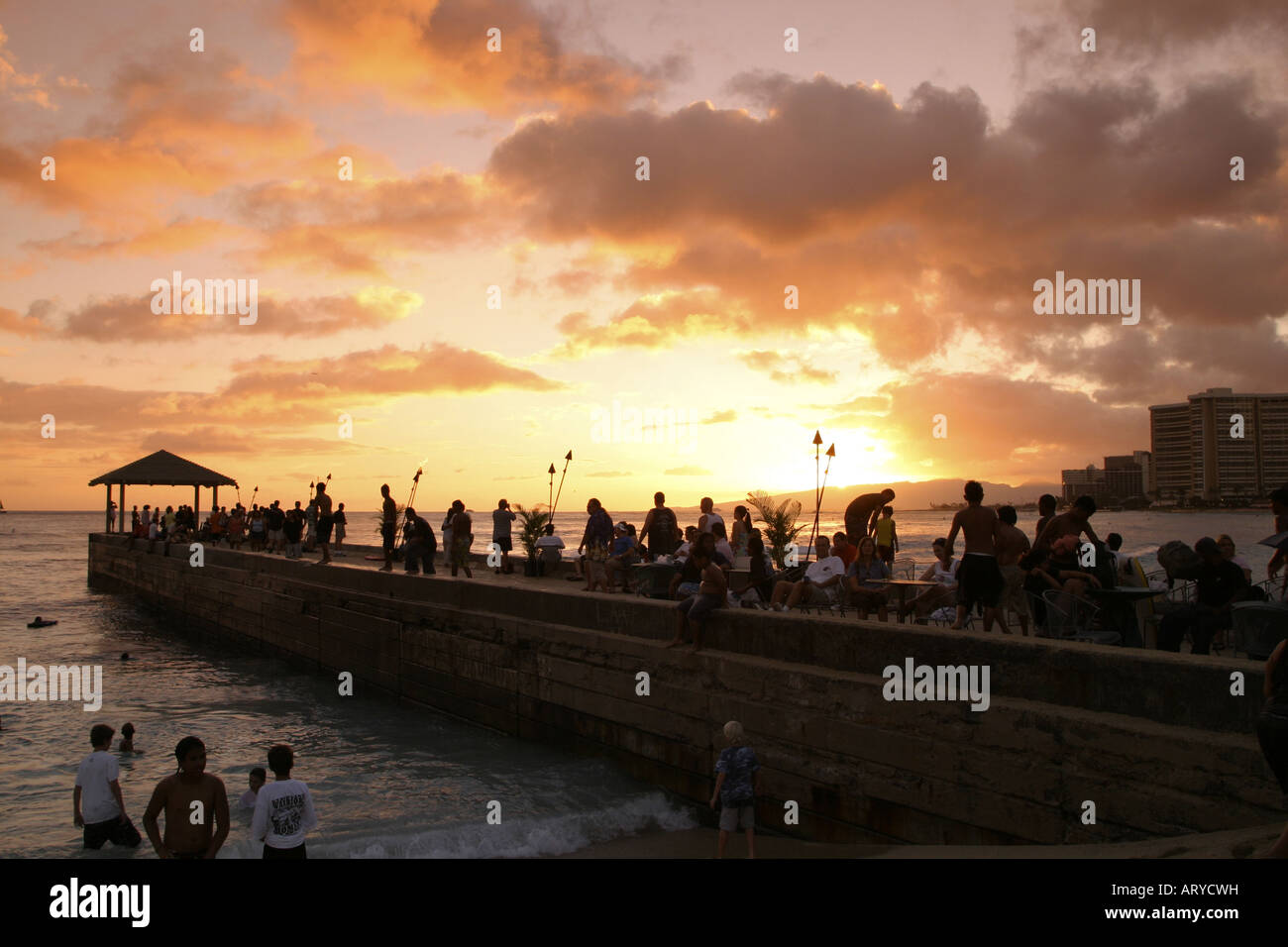 Les gens se rassemblent pour voir un autre beau coucher de soleil Hawaïen de la jetée au Kuhio Beach Park à côté de la plage de Waikiki, Oahu. Banque D'Images