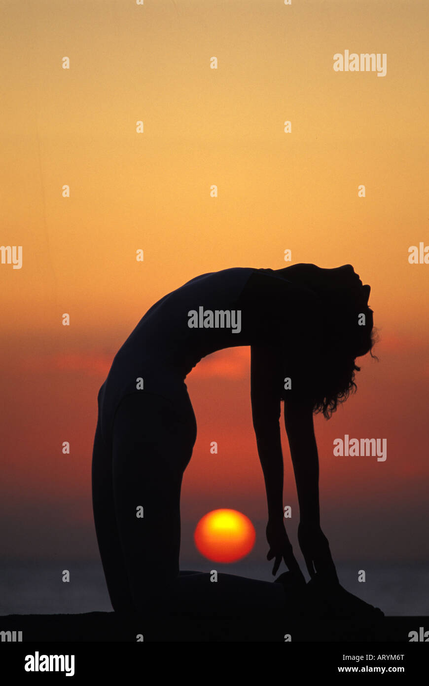 Femme dans la posture yoga au coucher du soleil Banque D'Images