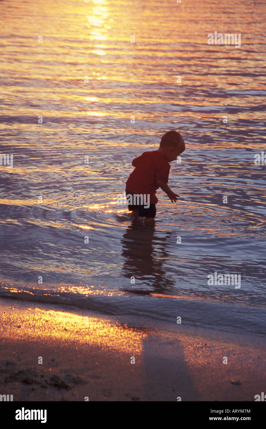 Jeune garçon jouant dans l'eau à l'Ala Moana Beach Park au coucher du soleil, Honolulu, Oahu Banque D'Images