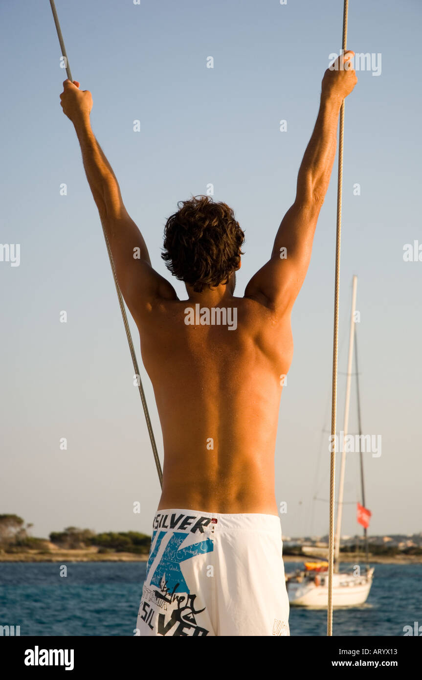L'homme se balançant de corde à bord d'un bateau à voile Banque D'Images
