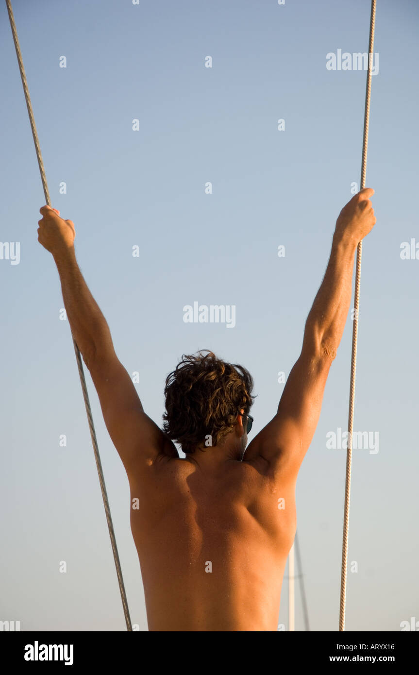 L'homme se balançant de corde à bord d'un bateau à voile Banque D'Images