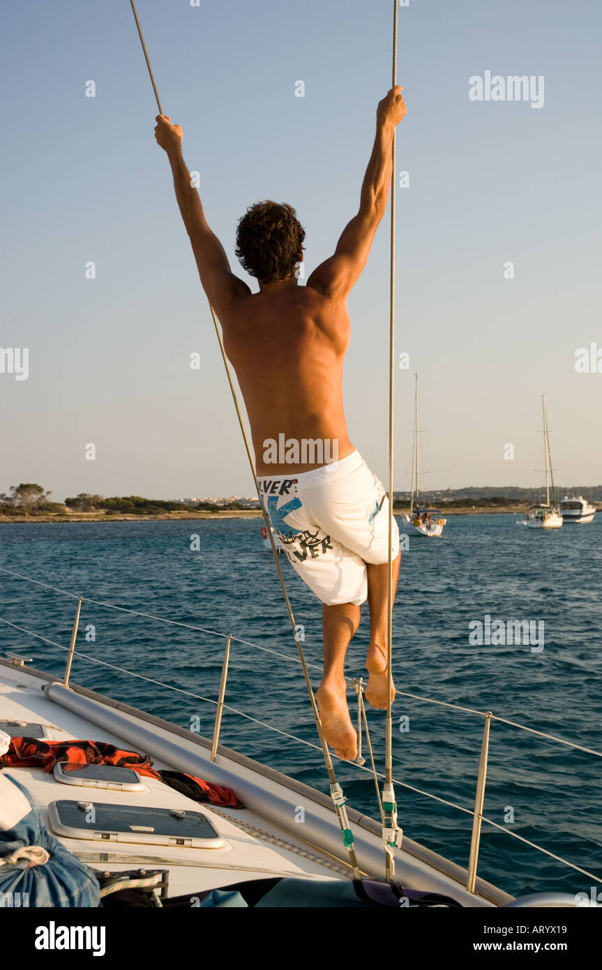 L'homme se balançant de corde à bord d'un bateau à voile Banque D'Images