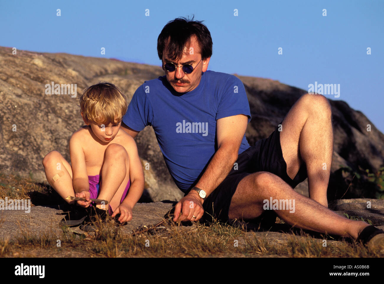 Père et fils jouant sur la roche en vacances, New York, USA Banque D'Images