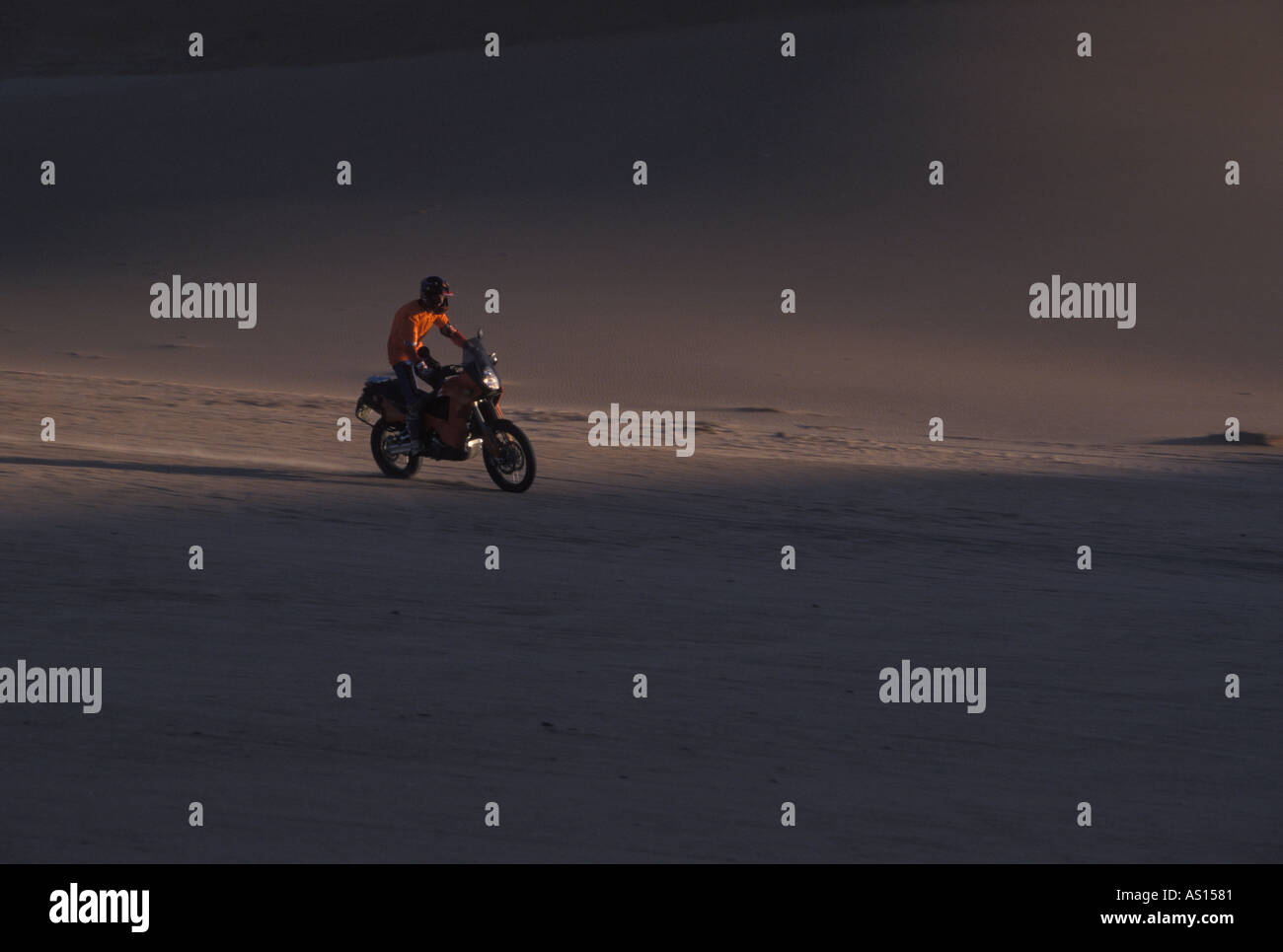 Équitation à travers motocycliste au coucher du soleil du désert Banque D'Images