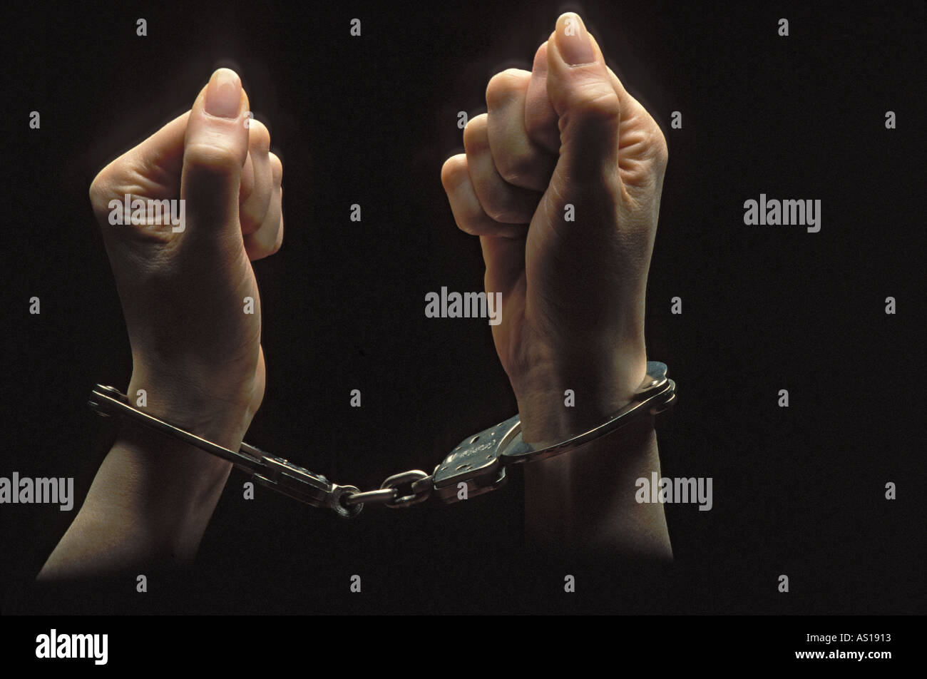 Les mains de la femme emprisonnée dans les tenailles d'poings menottés et silhouetté sur fond noir Banque D'Images