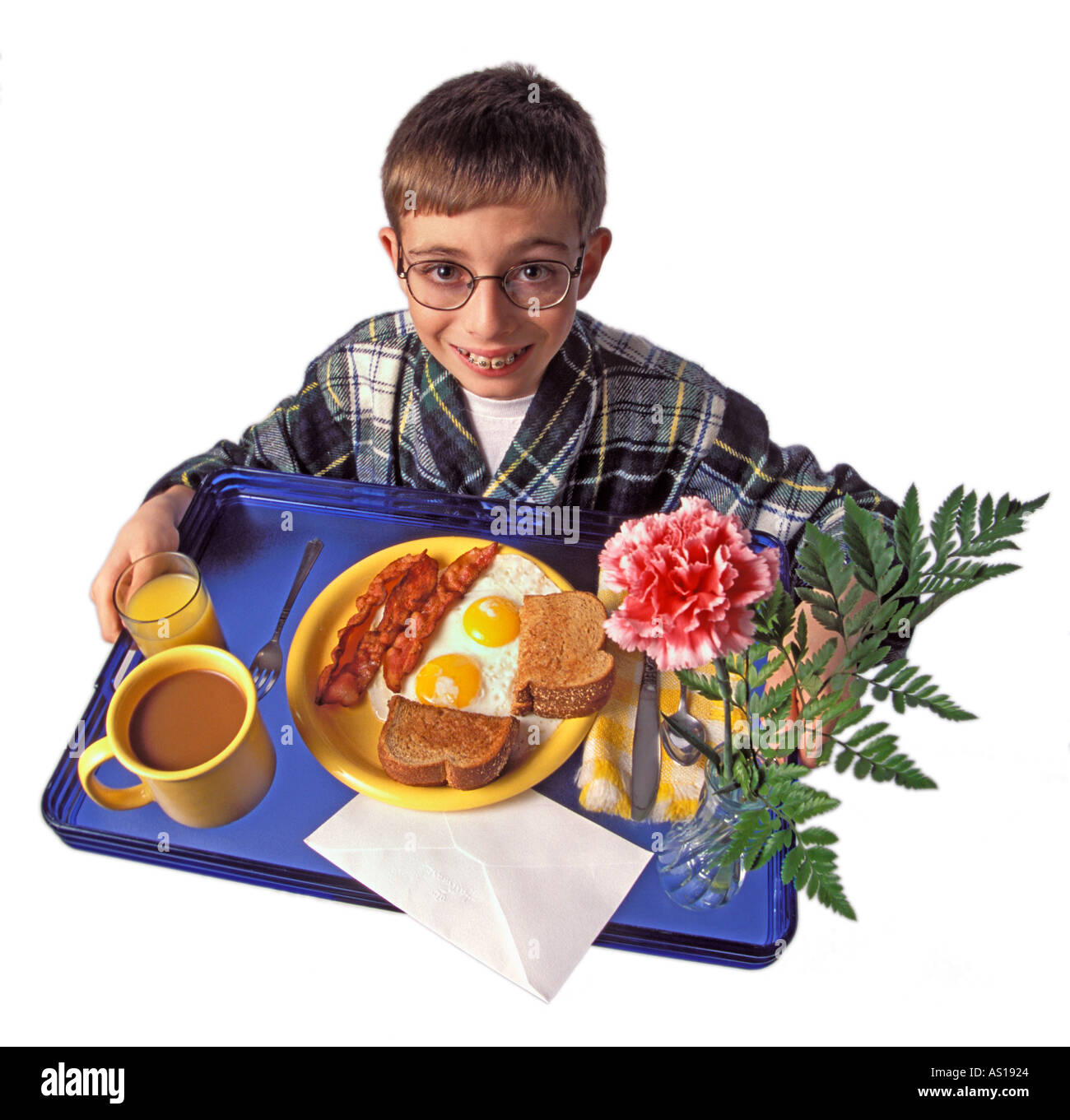 Boy holding petit-déjeuner au lit le bac se découpant sur fond blanc Banque D'Images