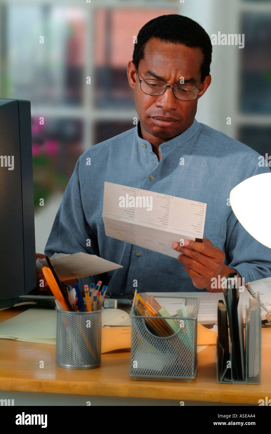 African American man travaillant dans un bureau à la maison et recevoir une facture par la poste Banque D'Images