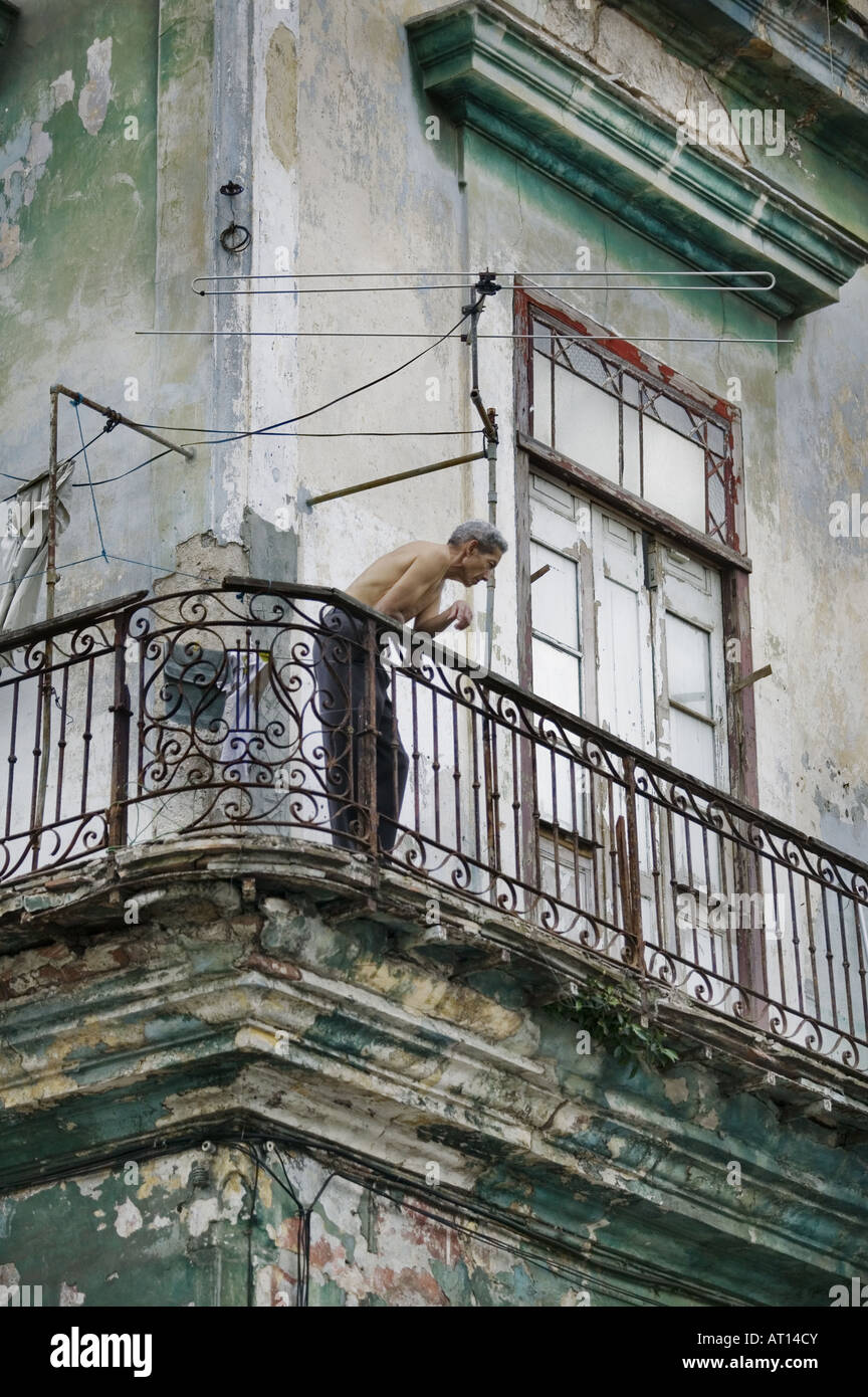 L'homme de Cuba, se penchant et regardant par-dessus son balcon à La Havane à Cuba. Banque D'Images