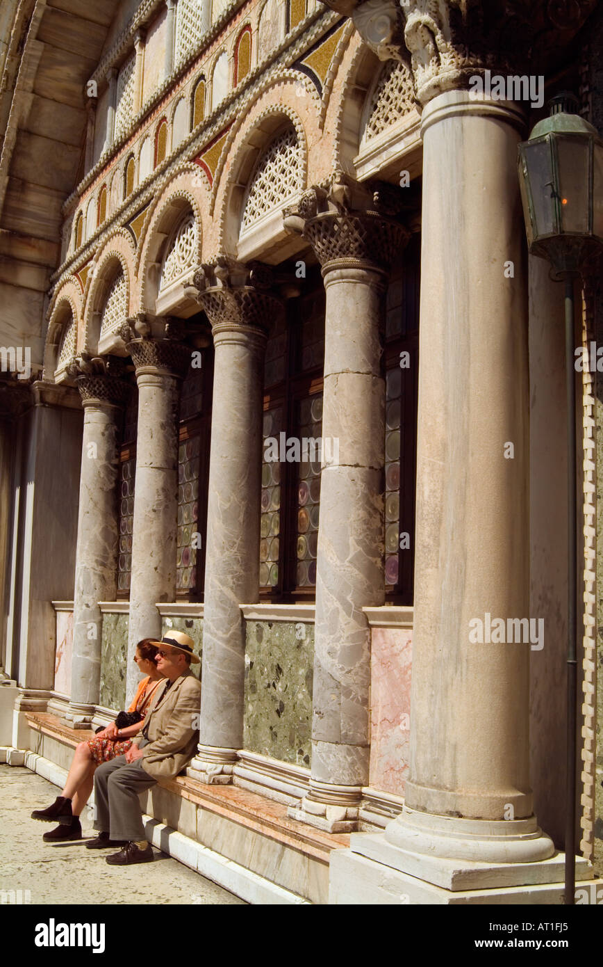 L'Italie, Venise, Couple sitting on ledge de la Basilique Saint Marc Banque D'Images