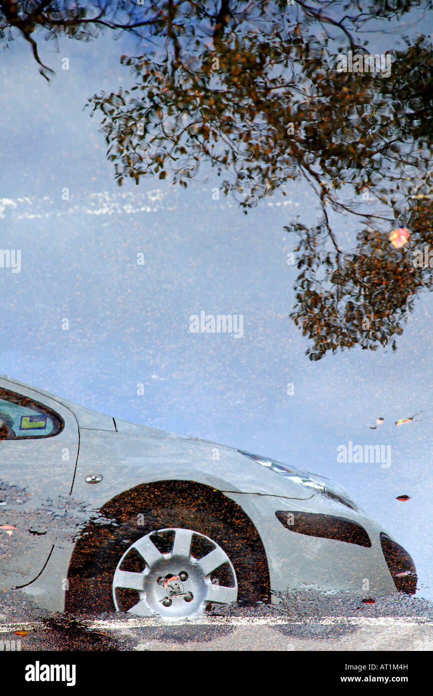 Une voiture blanche reflète dans une grande flaque d'eau Banque D'Images