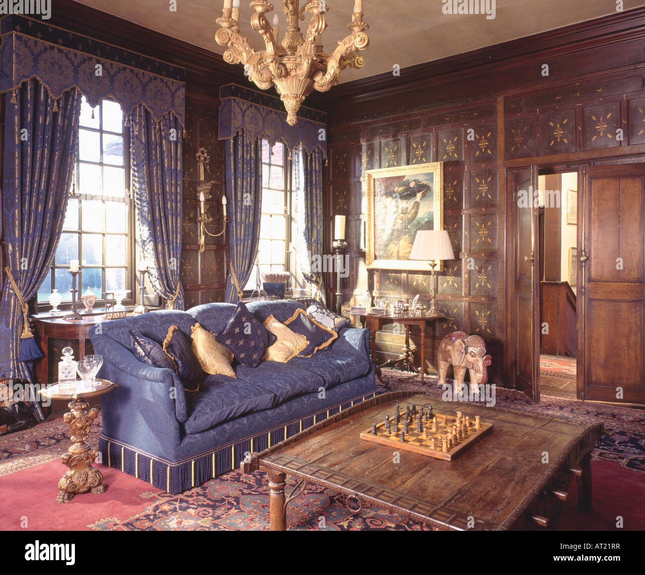 Conseil d'échecs sur la table en bois dans le salon lambrissé avec canapé bleu et bleu et or avec des rideaux cantonnières Banque D'Images