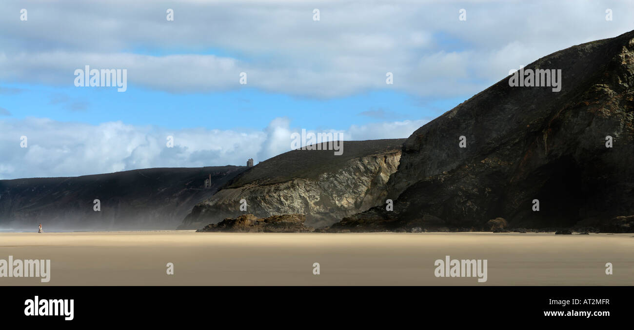 Un couple dans la distance embrasser sur une vaste plage de Cornouailles avec cliffs fluffy clouds and blue sky Banque D'Images