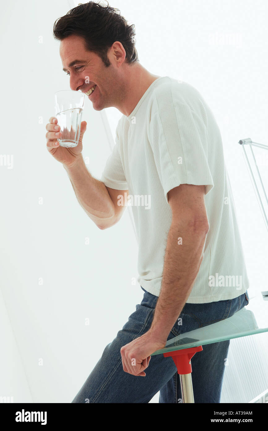 Un homme tenant un verre d'eau à la bouche smiling Banque D'Images