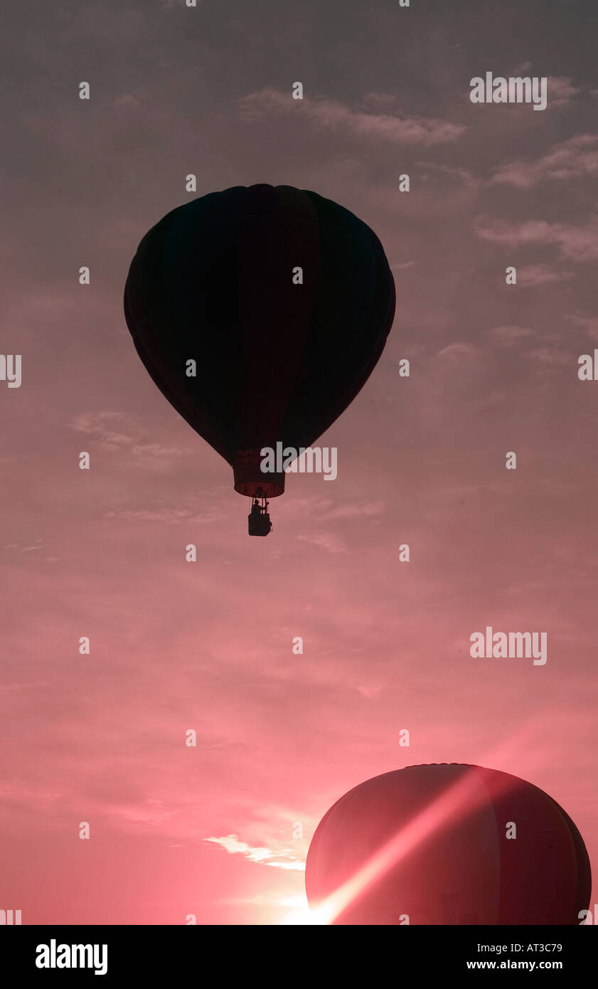 Deux ballons à air chaud qui se profile et le décollage contre soleil levant Banque D'Images