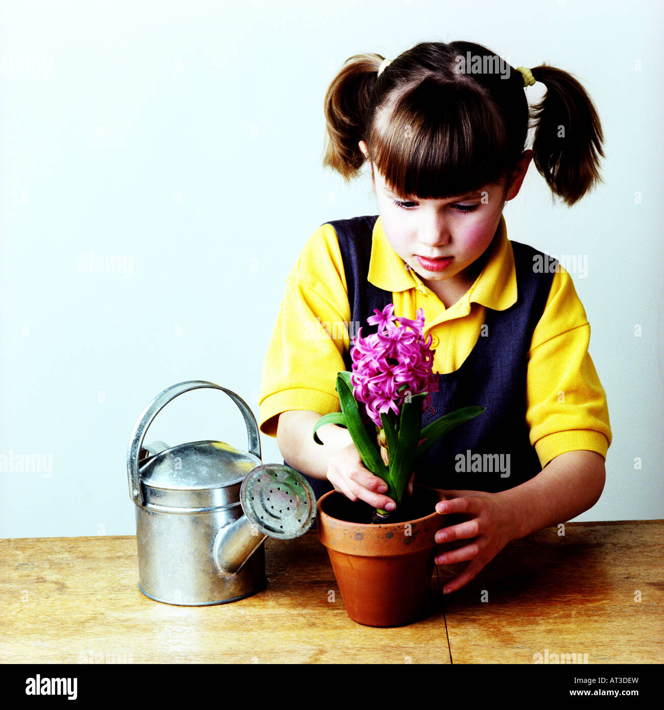 Une petite fille d'une plante en pot Banque D'Images