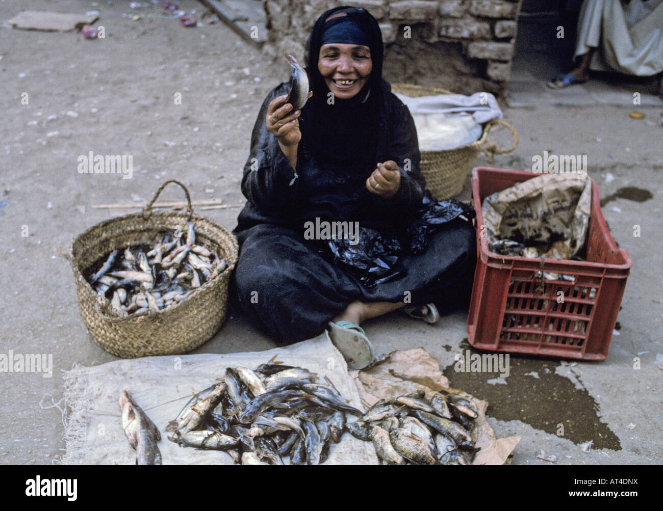 Femme égyptienne en noir robe traditionnelle arabe à la vente du poisson dans la rue près du marché à Louxor Egypte Banque D'Images