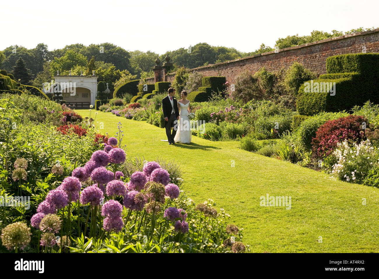 UK Cheshire Arley Hall couple nouvellement marié marche à travers le jardin des plantes herbacées Banque D'Images