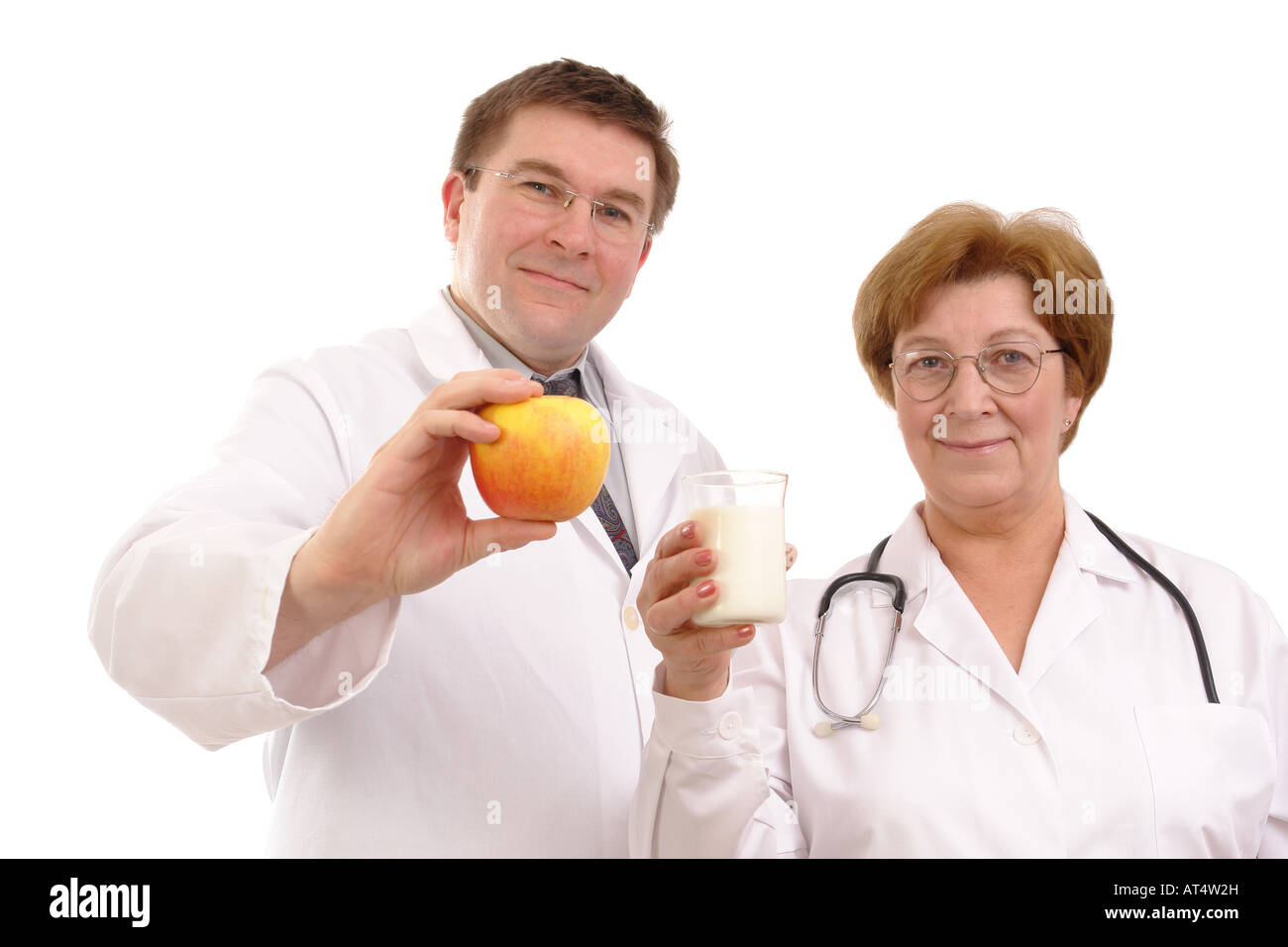 Young male doctor holding apple et senior female doctor holding verre de lait isolé sur fond blanc Banque D'Images