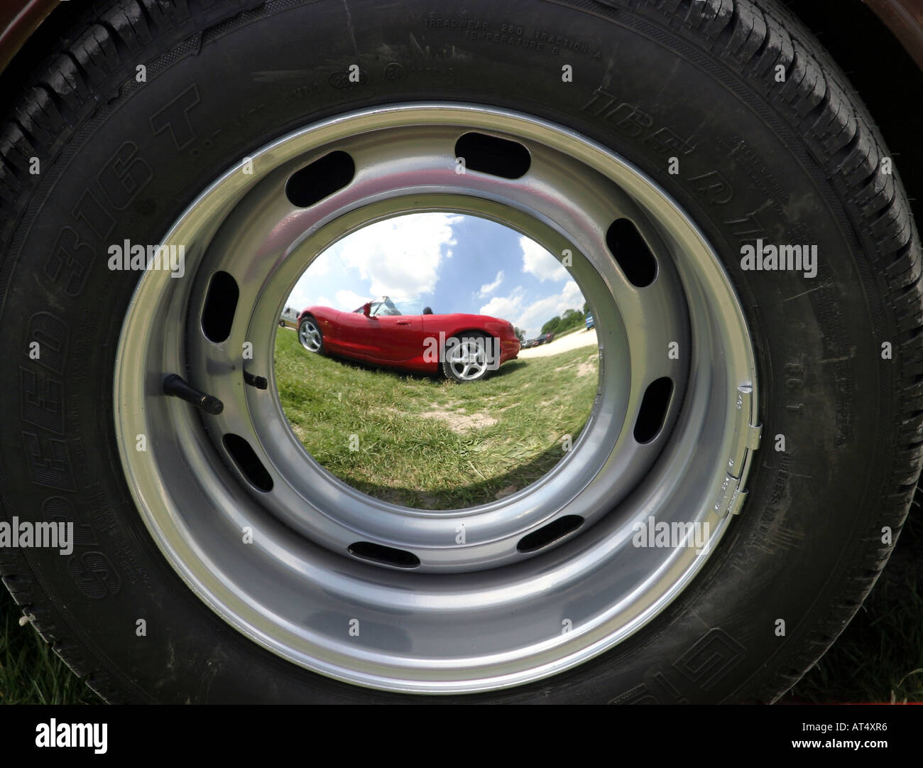 Voiture sport rouge reflète dans une voiture ancienne roue chromée de moyeu. Banque D'Images