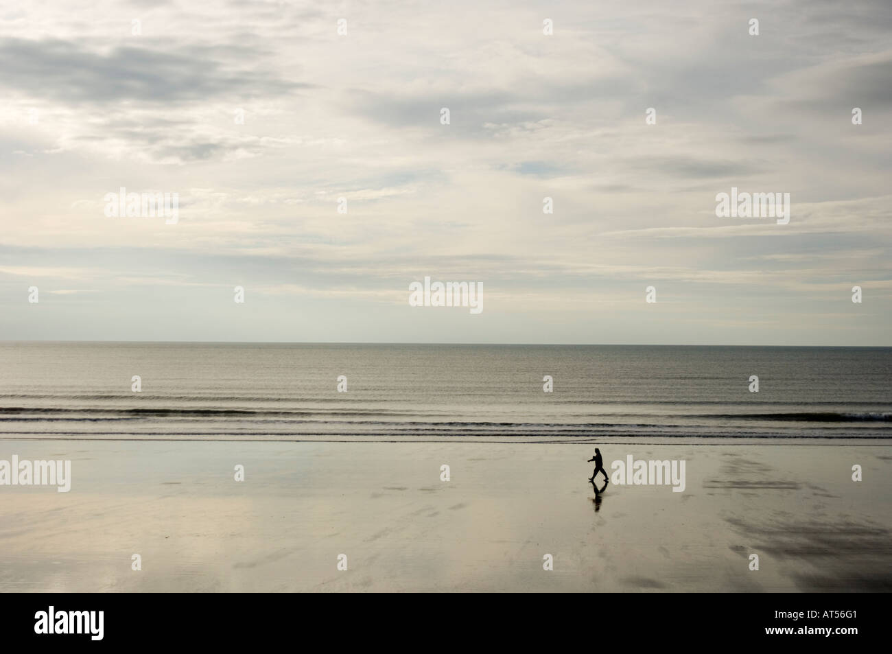 Seule personne qui marche seul sur la plage déserte en automne ou en hiver à marée basse, Borth Ceredigion Pays de Galles UK Banque D'Images