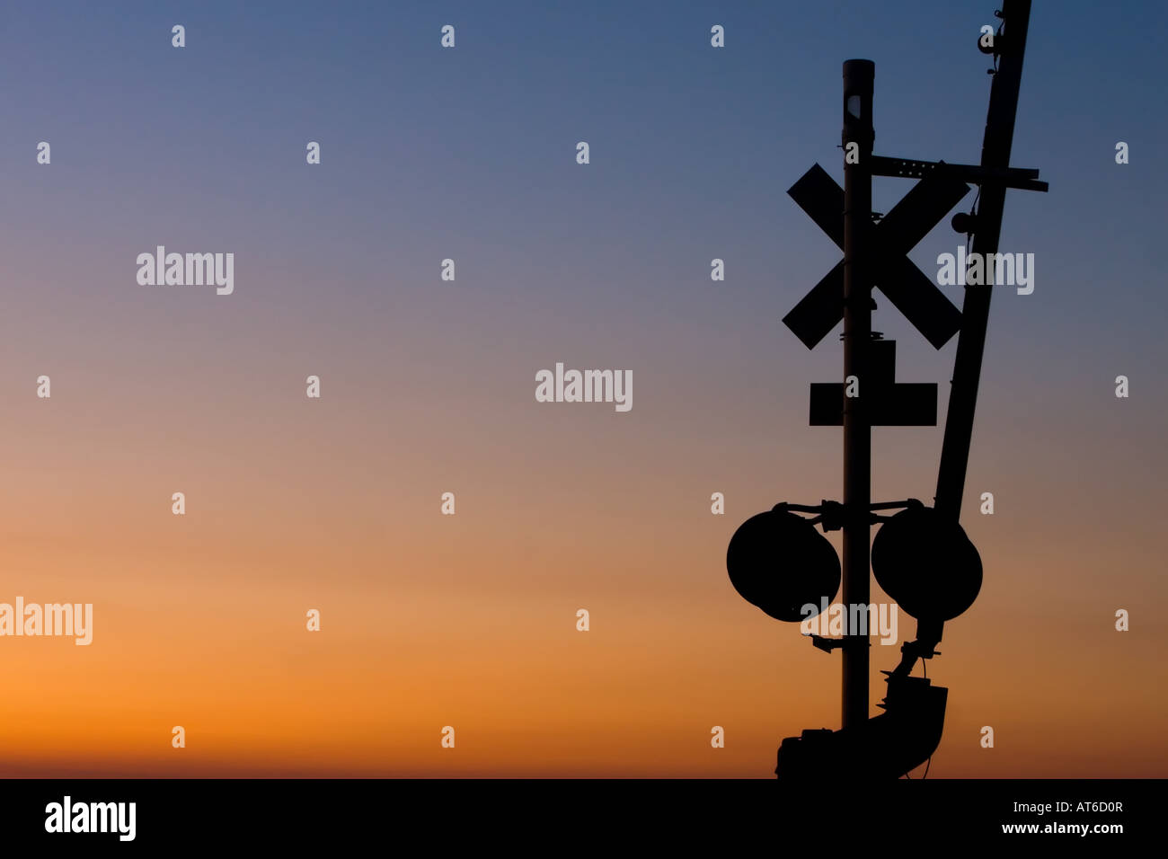 Le coucher du soleil les silhouettes la protection des passages à niveau à un passage à niveau. Banque D'Images