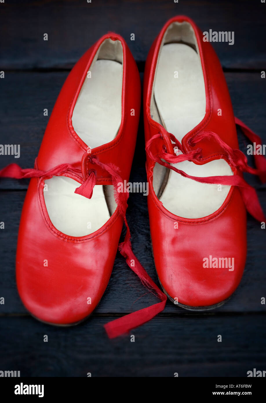 Une paire de chaussures de robinet rouge vintage tourné contre un plancher en bois sombre poli Banque D'Images