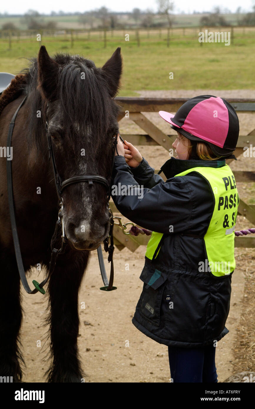 Young Pony Rider Réglage de la bride sur la tête de son animal de compagnie Banque D'Images