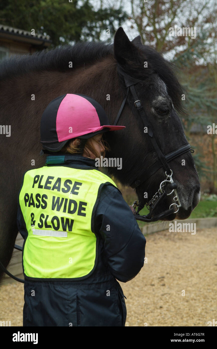 Pony Rider portant veste de sécurité inscrits Veuillez passer lentement l'échelle Little Girl holding son animal Poney Cob Banque D'Images