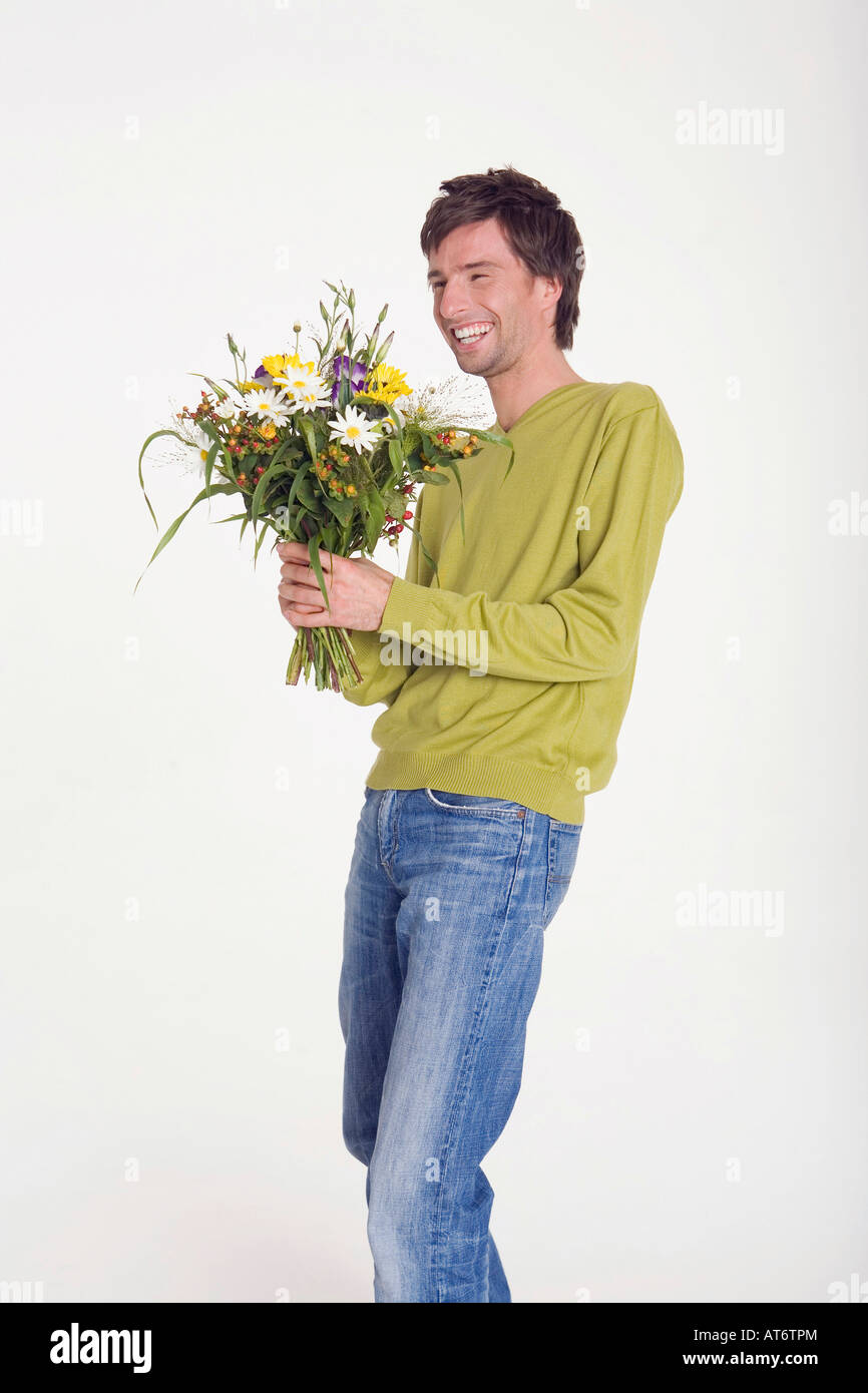 Young man holding bunch of flowers, smiling, portrait Banque D'Images
