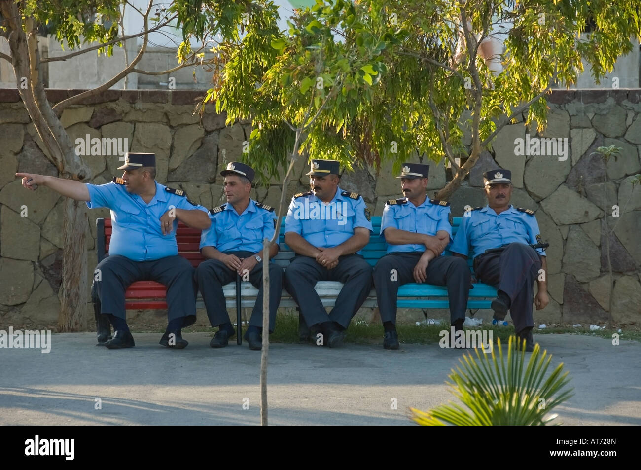 Un groupe de policiers assis sur un banc à Bakou, Azerbaïdjan, avec un homme pointant Banque D'Images