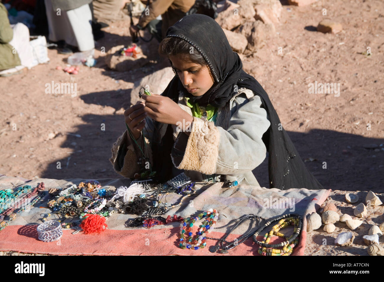 Désert du Sinaï Egypte Afrique du Nord une jeune fille bédouine Février faire le tri des bibelots disposés sur un mur à vendre Banque D'Images