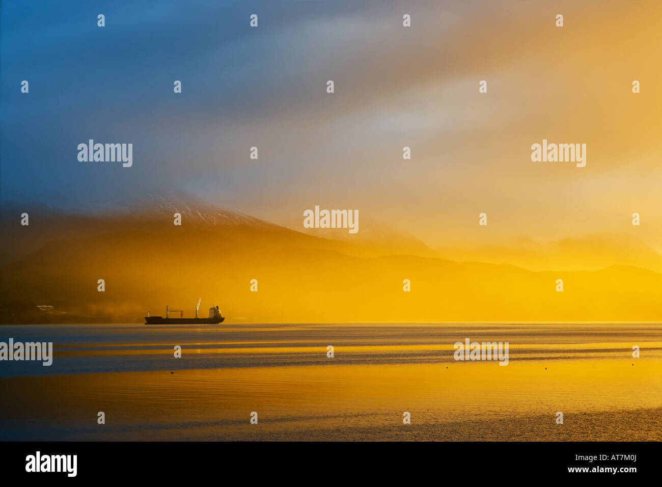 Lever de soleil spectaculaire sur un matin brumeux dans le port d'Ushuaia sud de l'Argentine avec un cargo dans la distance Banque D'Images