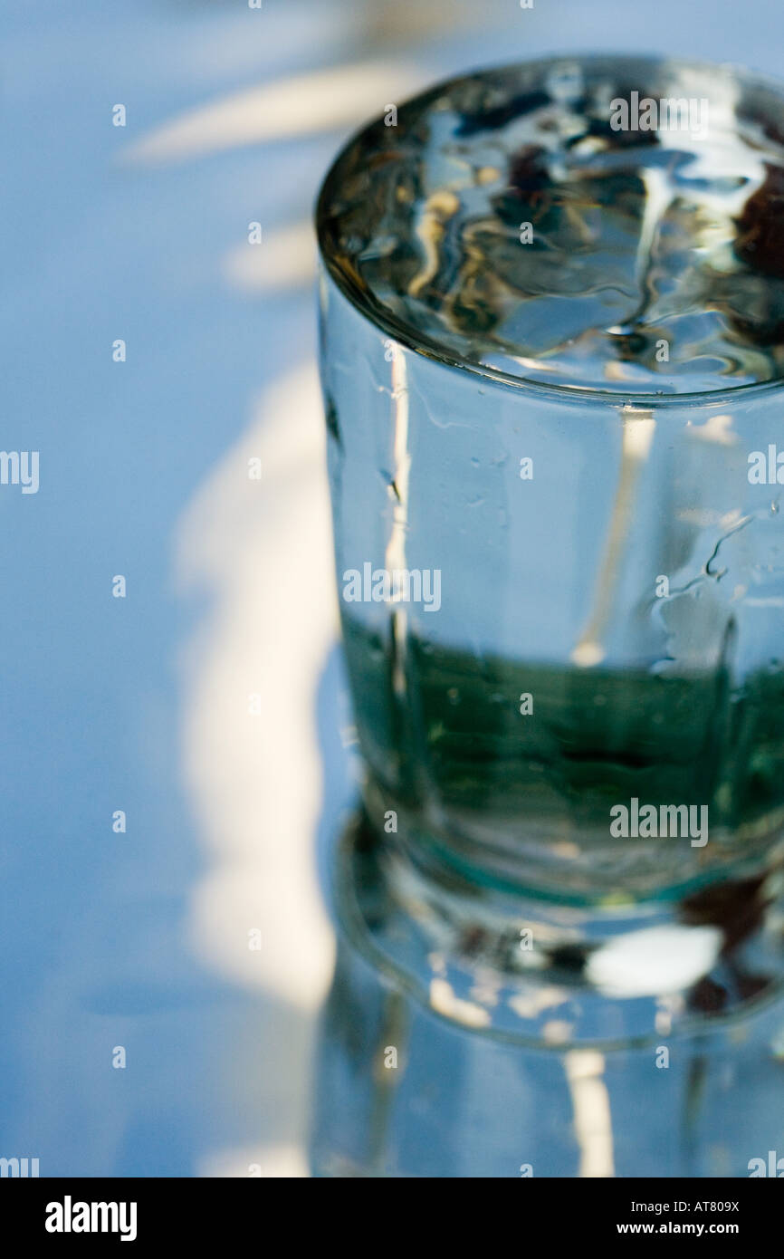 Verser de l'eau dans un verre qui se dresse sur un miroir Banque D'Images