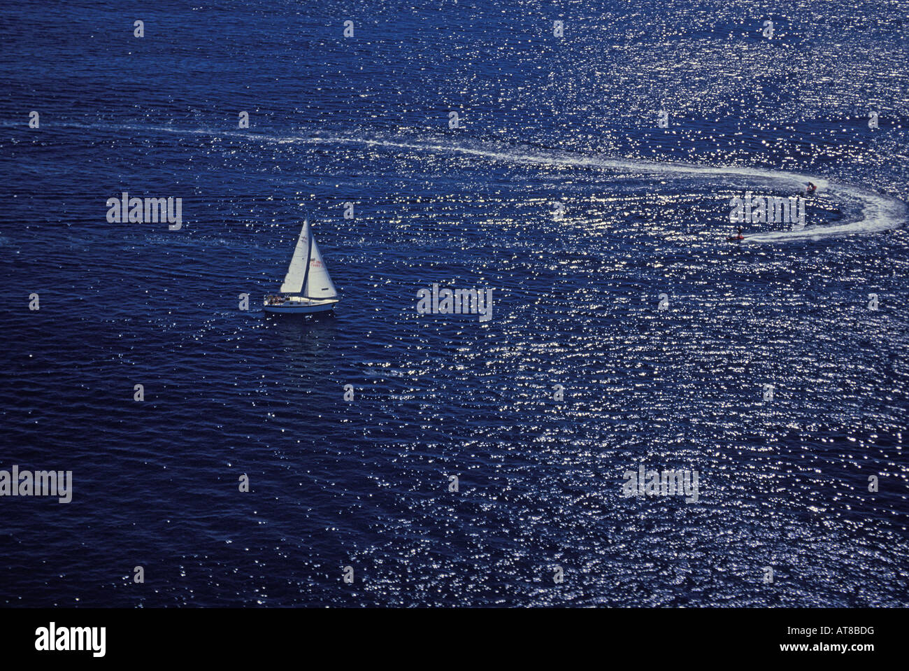 Deux skieurs jet créer un service circulaire blanc alors qu'un voilier d'écumage pacifiquement l'océan bleu acier à proximité. Banque D'Images