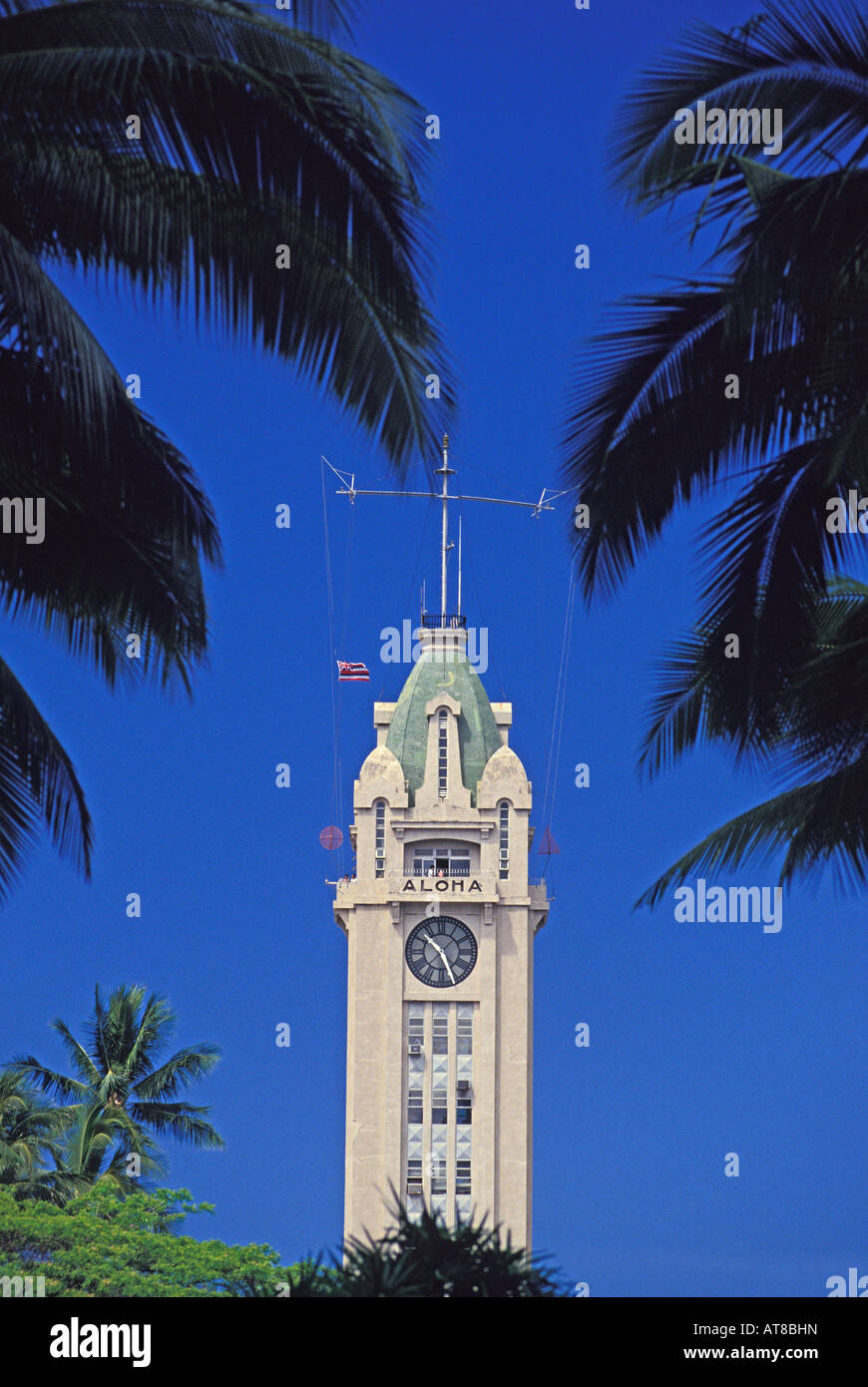 Aloha Tower encadrée par des palmiers avec ciel bleu. Banque D'Images