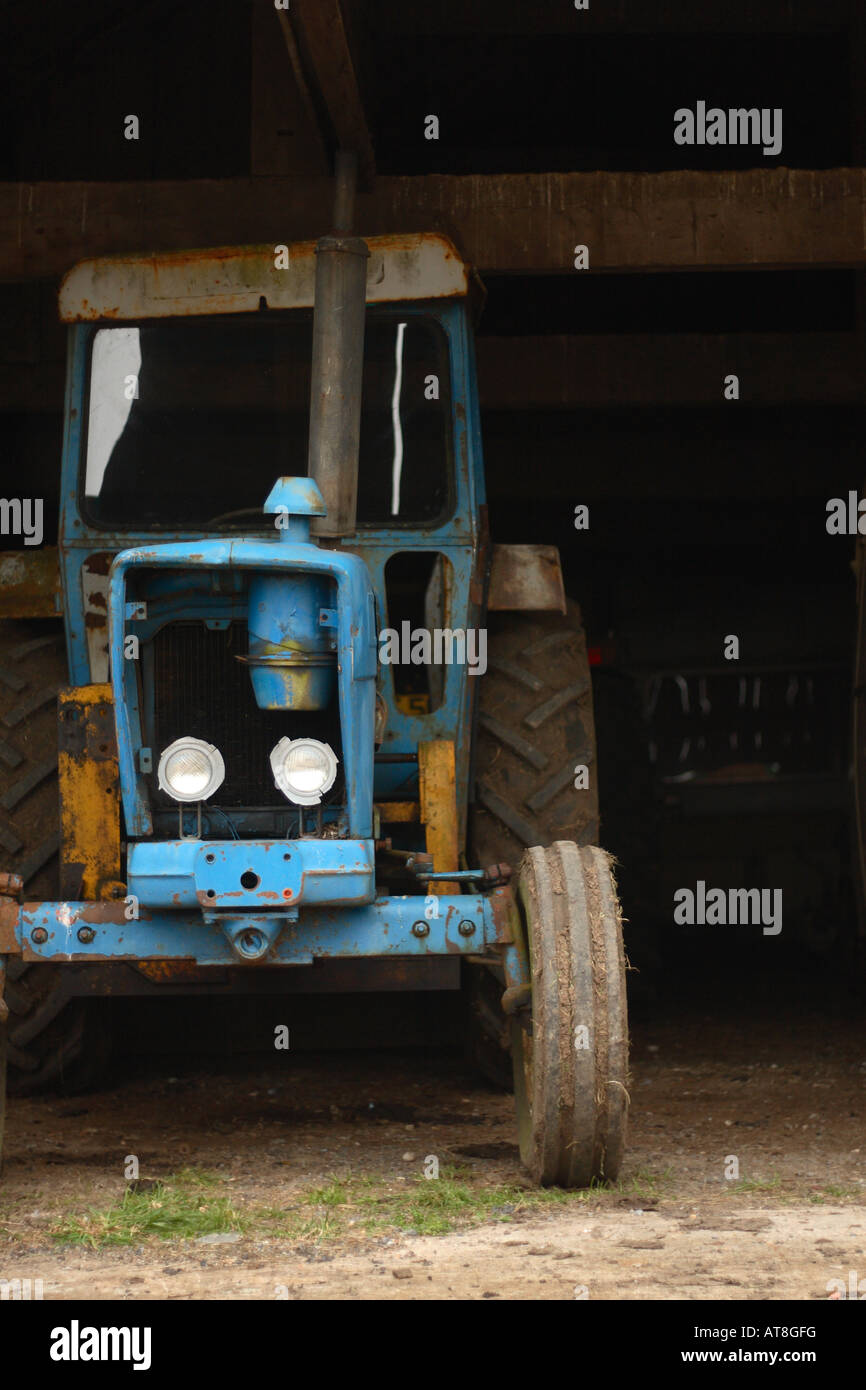 Sale vieux tracteur dans une grange de cour de ferme Banque D'Images Sale vieux tracteur dans une grange de cour de ferme Banque D'Images