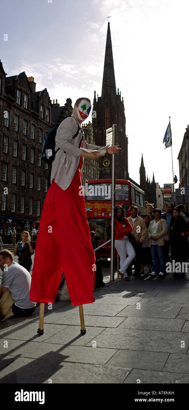 Artiste de rue sur échasses foule à l'arrêt de bus, High Street, Edinburgh Fringe Festival, Ecosse, Banque D'Images