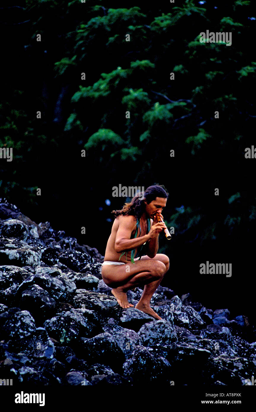 Local attrayant homme portant un tissu longe la lecture d'une flûte de bambou à côté d'Ulupo Heiau près de Kailua sur le côté au vent d'Oahu Banque D'Images