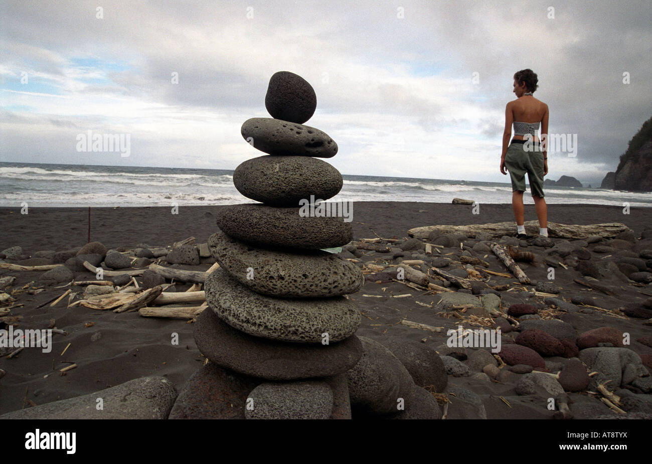 Jeune femme debout près de rock alter, plage de sable noir, Pololu Kohala Nord, Big Island Banque D'Images