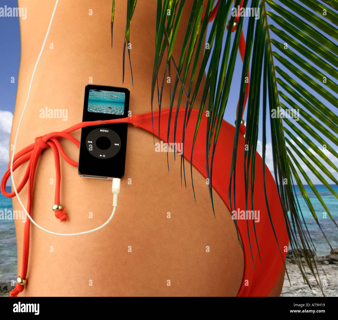Femme avec l'iPod nano au red bikini élastique en décor tropical Banque D'Images