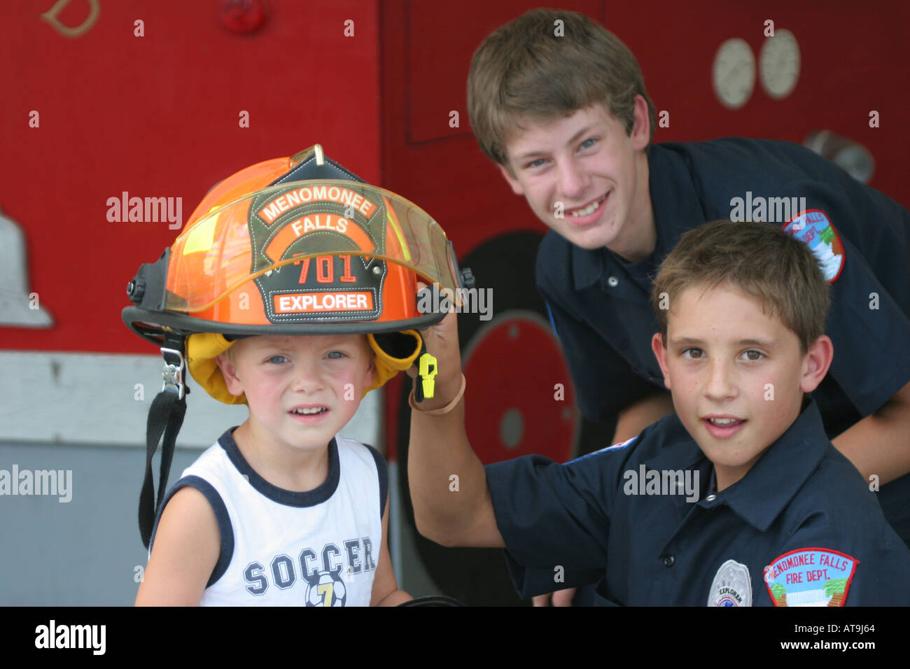 Deux futurs pompiers et un jeune garçon qui pourrait être un futur pompier et porte un casque explorateurs orange Banque D'Images