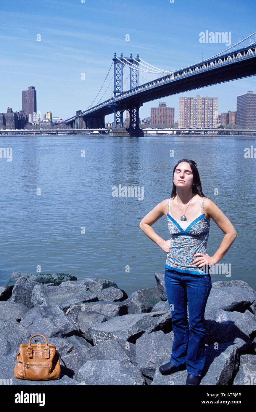 Une jeune femme se détendre au soleil, sous le pont de Manhattan, Dumbo, Brooklyn, New York City, USA. Banque D'Images