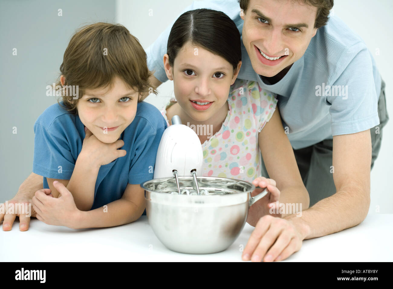 Son père et ses deux enfants, tous ensemble de cuisson smiling at camera Banque D'Images