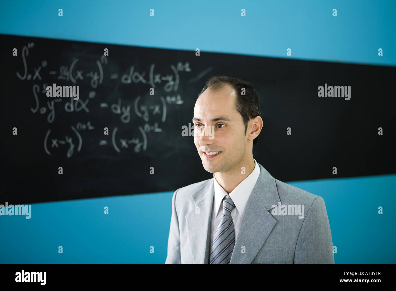 Man looking away, smiling, équation mathématique sur tableau noir en arrière-plan Banque D'Images
