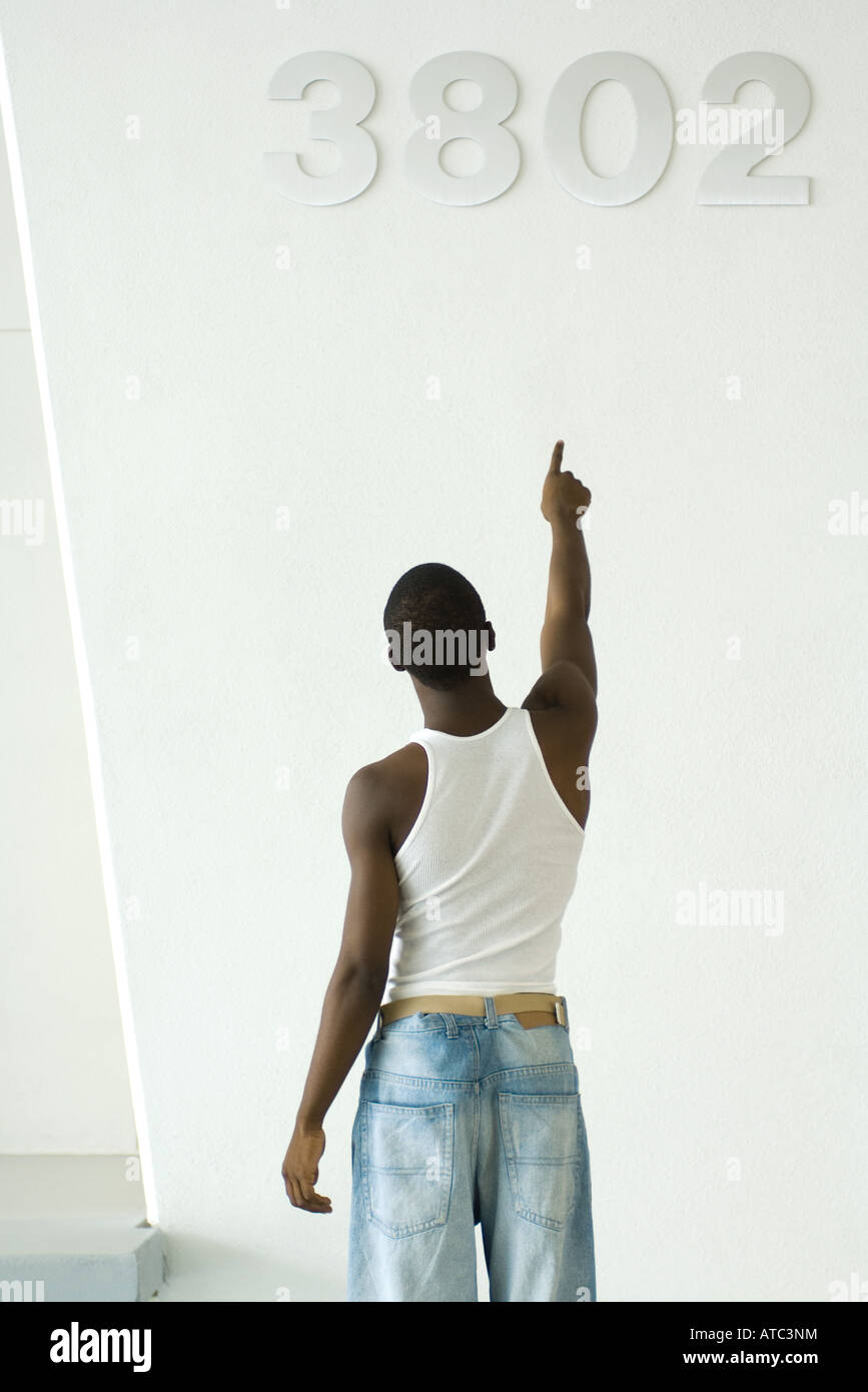 Teenage boy pointing at numéros sur mur, vue arrière Banque D'Images